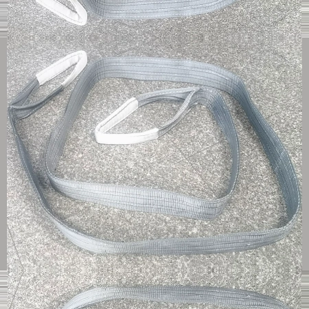 Grey 4 tonne single use webbing slings laid out on the workshop floor before packing
