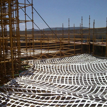 White safety net hung across the face of a scaffolding structure under a blue sky