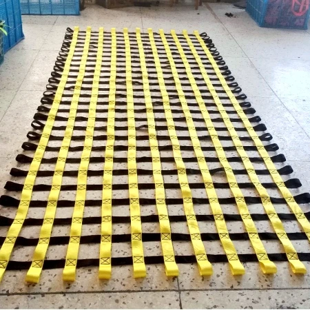 Yellow webbing net laid out flat on a concrete floor with black cross straps stitched at each intersection