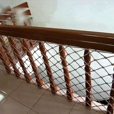 Raking staircase net infill following the stair pitch Staircase safety net running along the rake of a curved stair as infill below a timber handrail