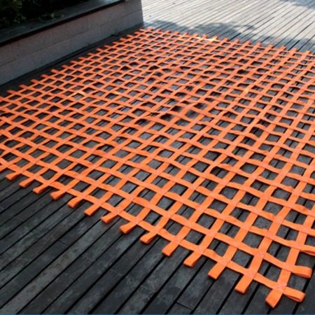 Orange webbing climbing net laid flat on a timber deck showing the square mesh and edge