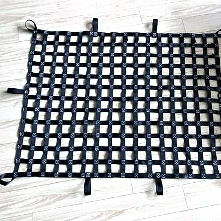 Black webbing truck cargo net laid flat on a light floor showing the square mesh and corner tabs